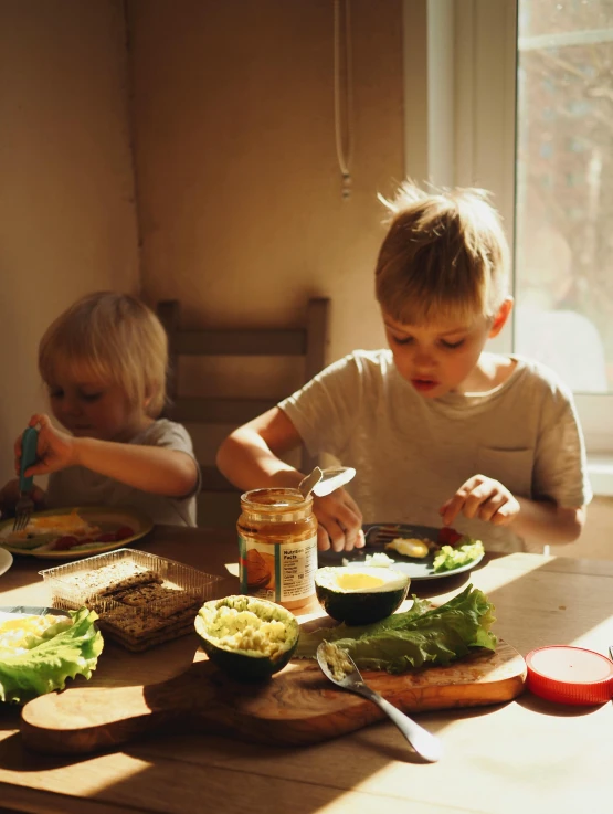 two children sit at a table eating a meal