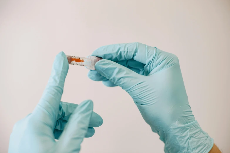 someone wearing blue gloves and a blue wristband holds a toothbrush in front of the camera