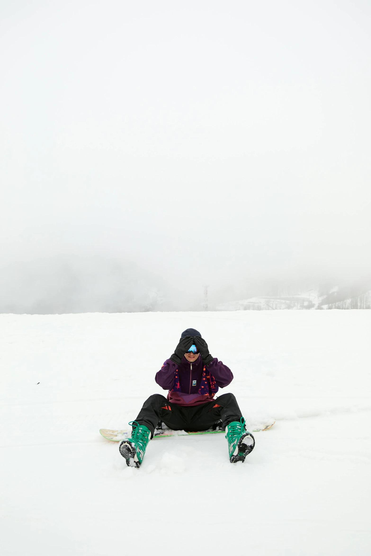 a woman sitting in the snow while wearing snowboards