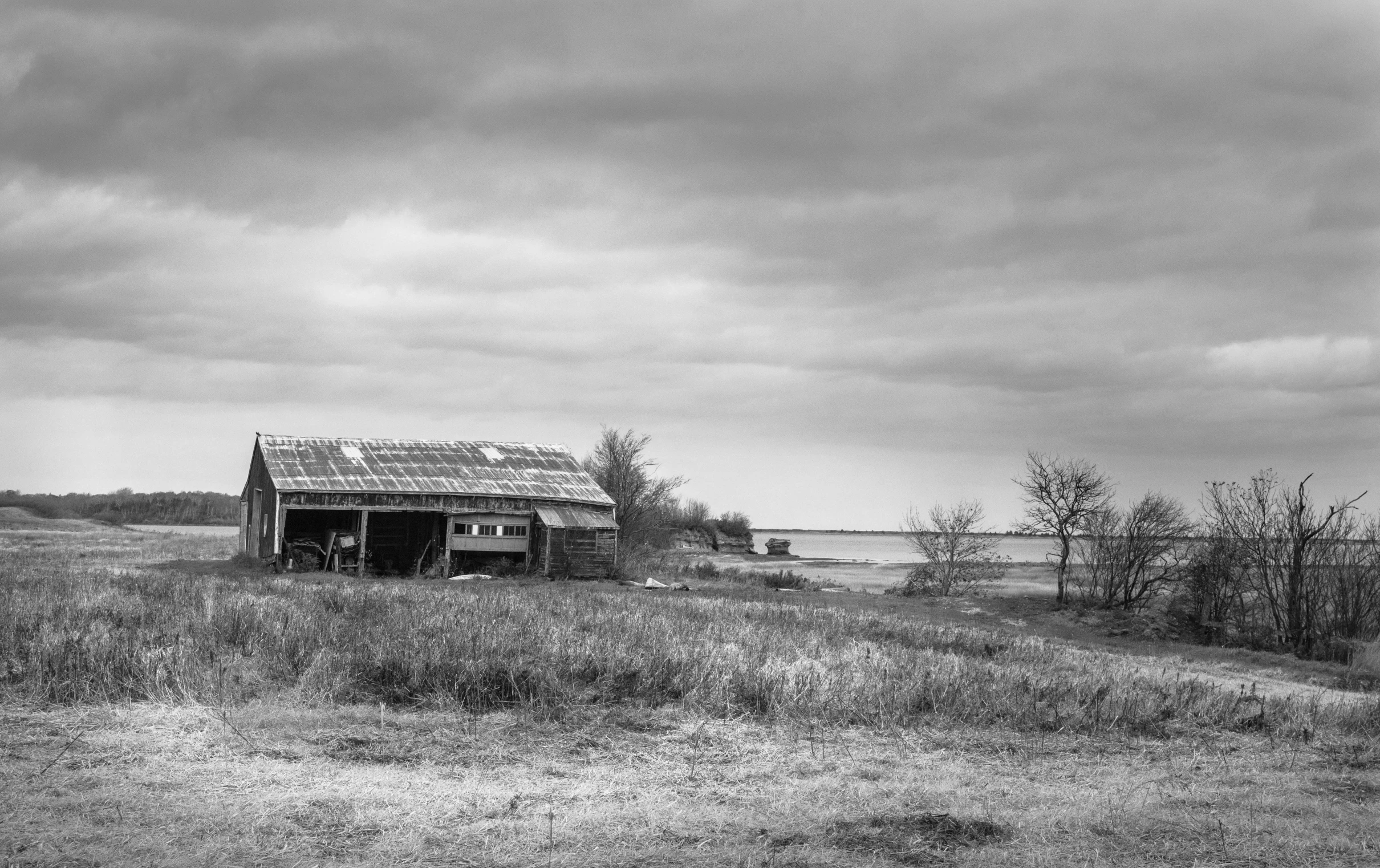 a old barn in a pasture with a cloudy sky