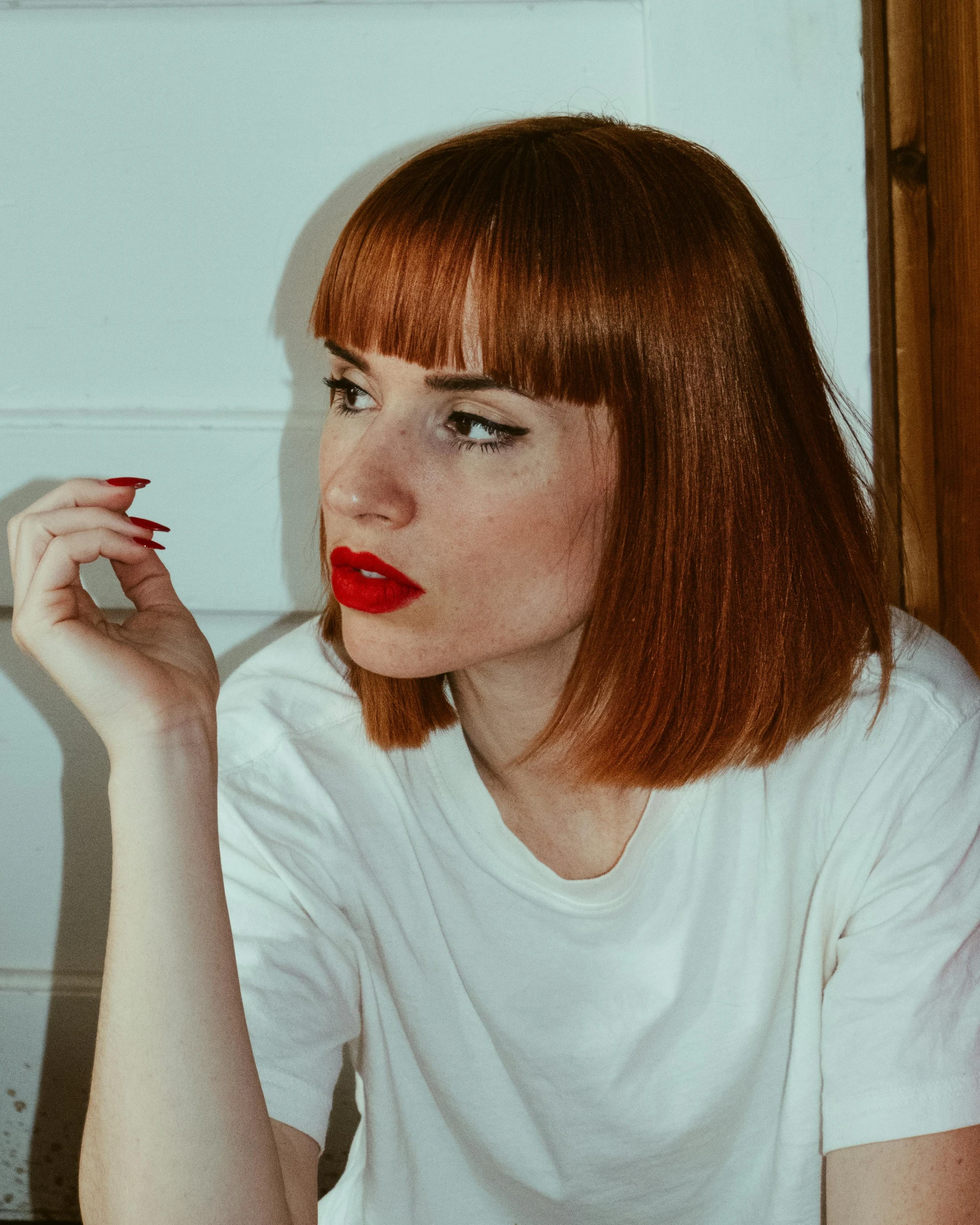 a woman is sitting at a table with her hand up to her chin