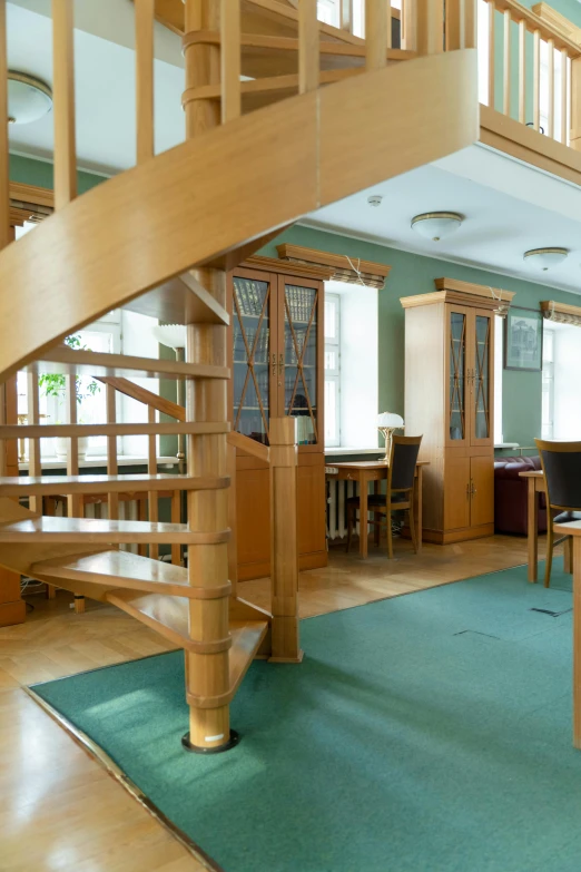 a modern looking home office with green carpet and wooden stairs