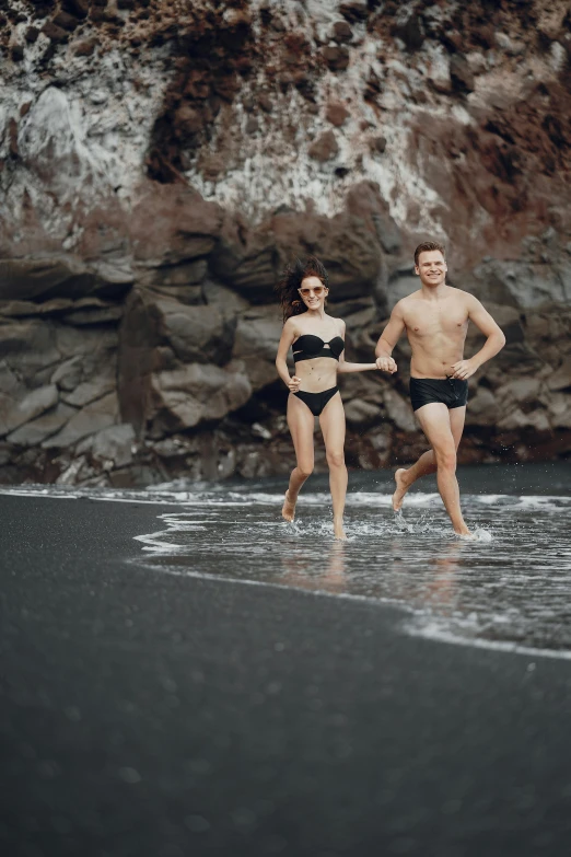 a man and woman running in the surf together