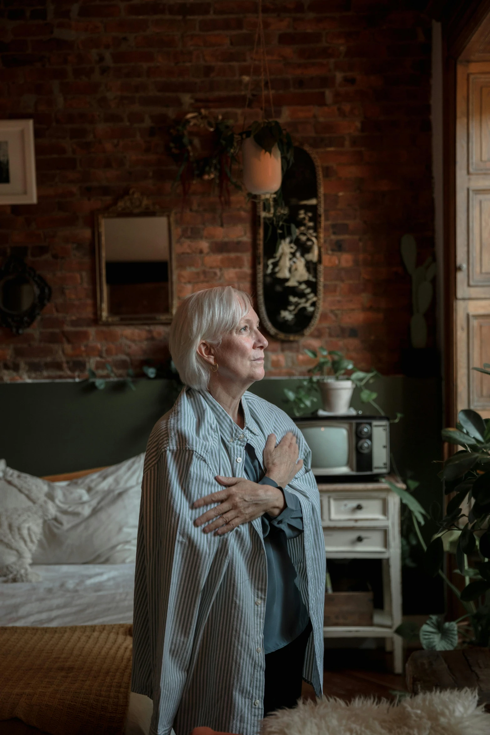 a woman in a white shirt standing by a bed