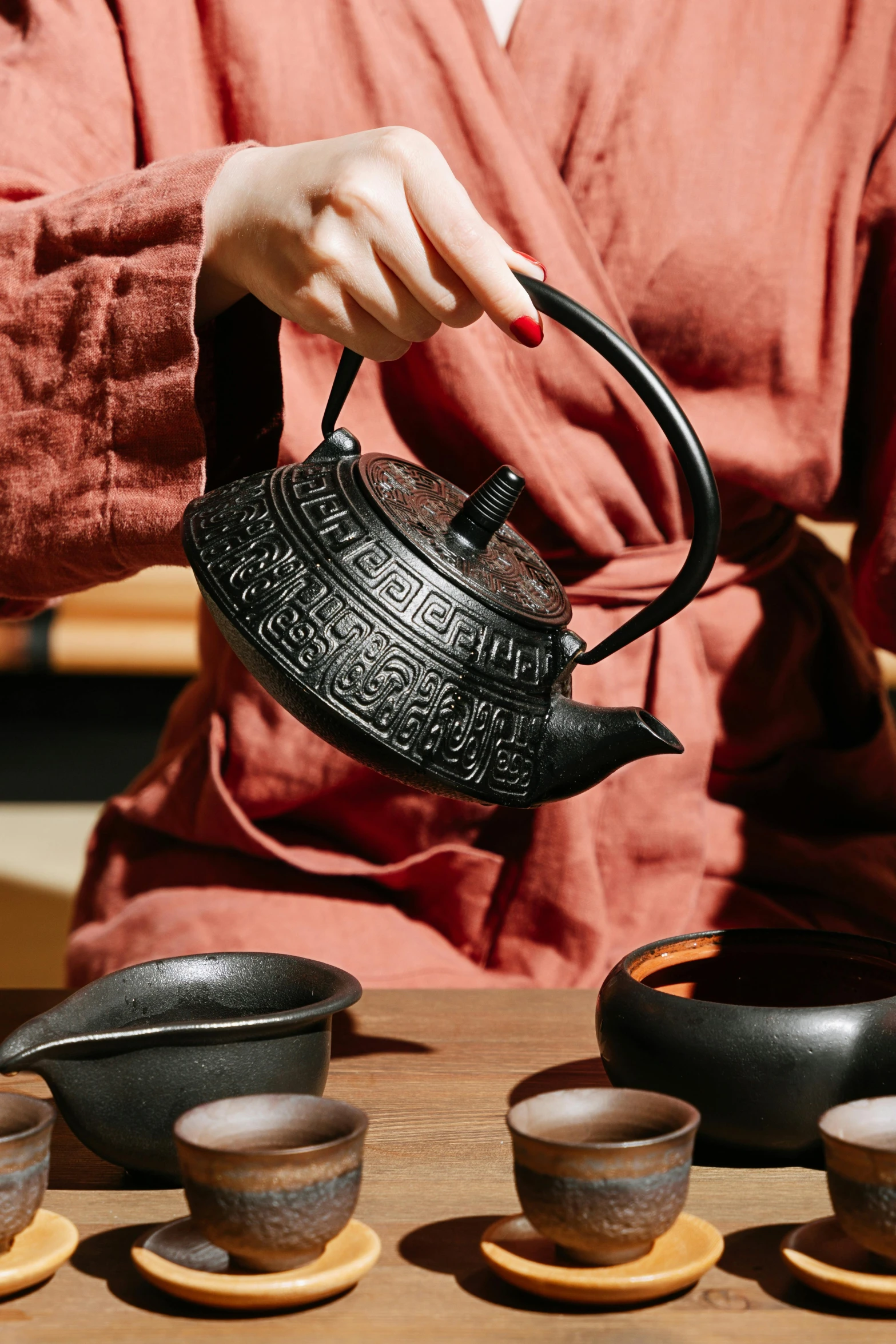 woman holding black teapot with matching black pots