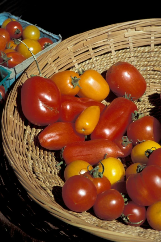 a basket filled with tomatoes and yellow peppers