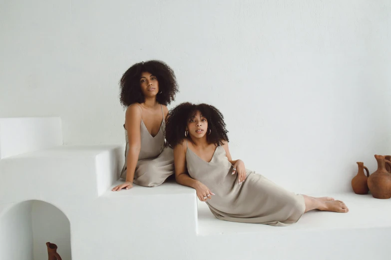 two woman sitting next to each other in white outfits