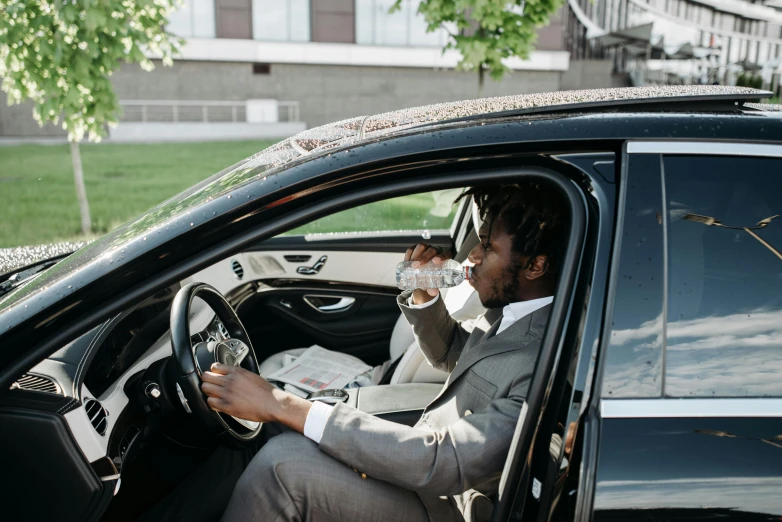 a man driving a black car with his hands on the steering wheel