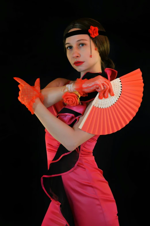 a girl dressed in a costume, holding up a red fan