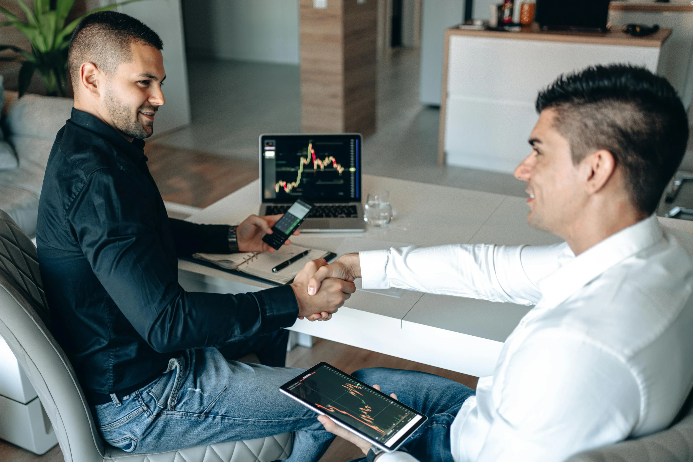 a man sitting at a desk shaking hands with another person