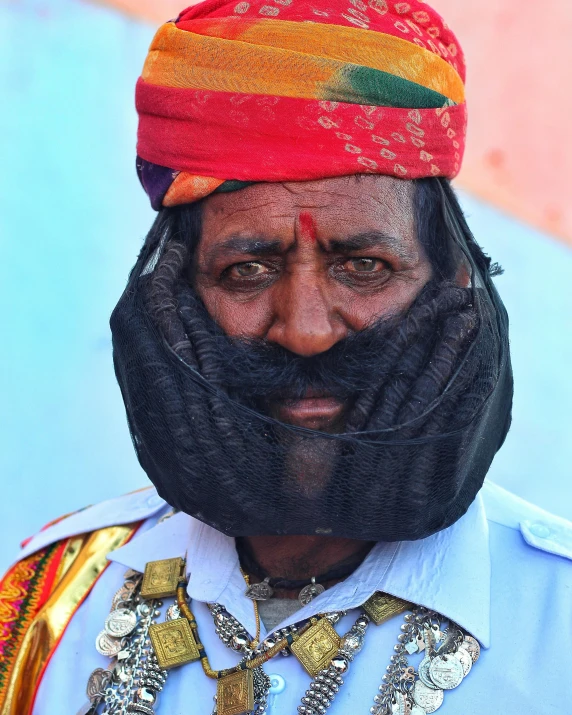 a man wearing a red, gold and blue headdress