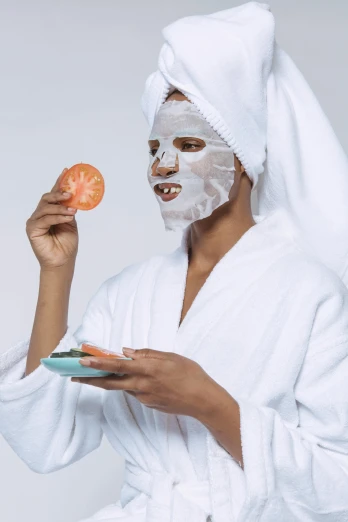 a woman with a white robe and orange is holding up a sandwich