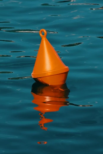 a single orange cone floats across blue water