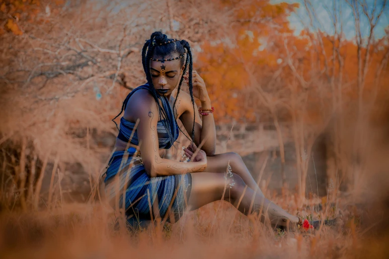 a woman with dreadlocks sitting in the grass