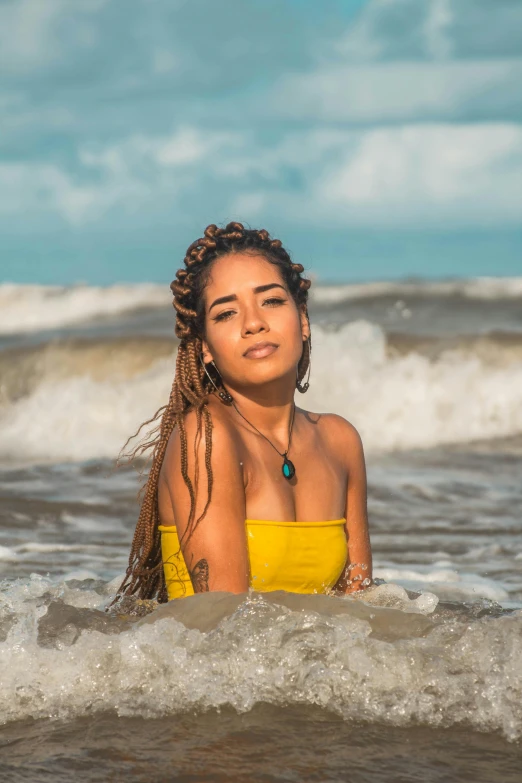 a woman wearing a yellow bikini stands in the ocean