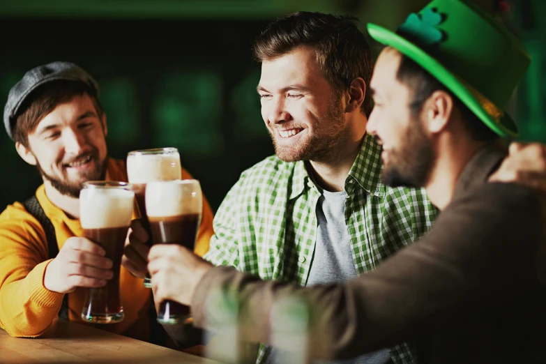 three men sitting around at a table with beer