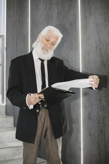 an old man in a suit and tie reading paper