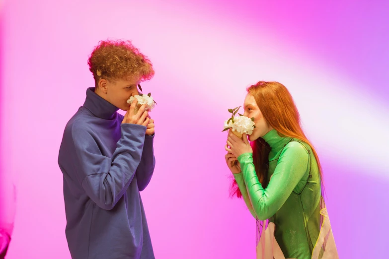 a woman in green and a man in blue looking at flower petals