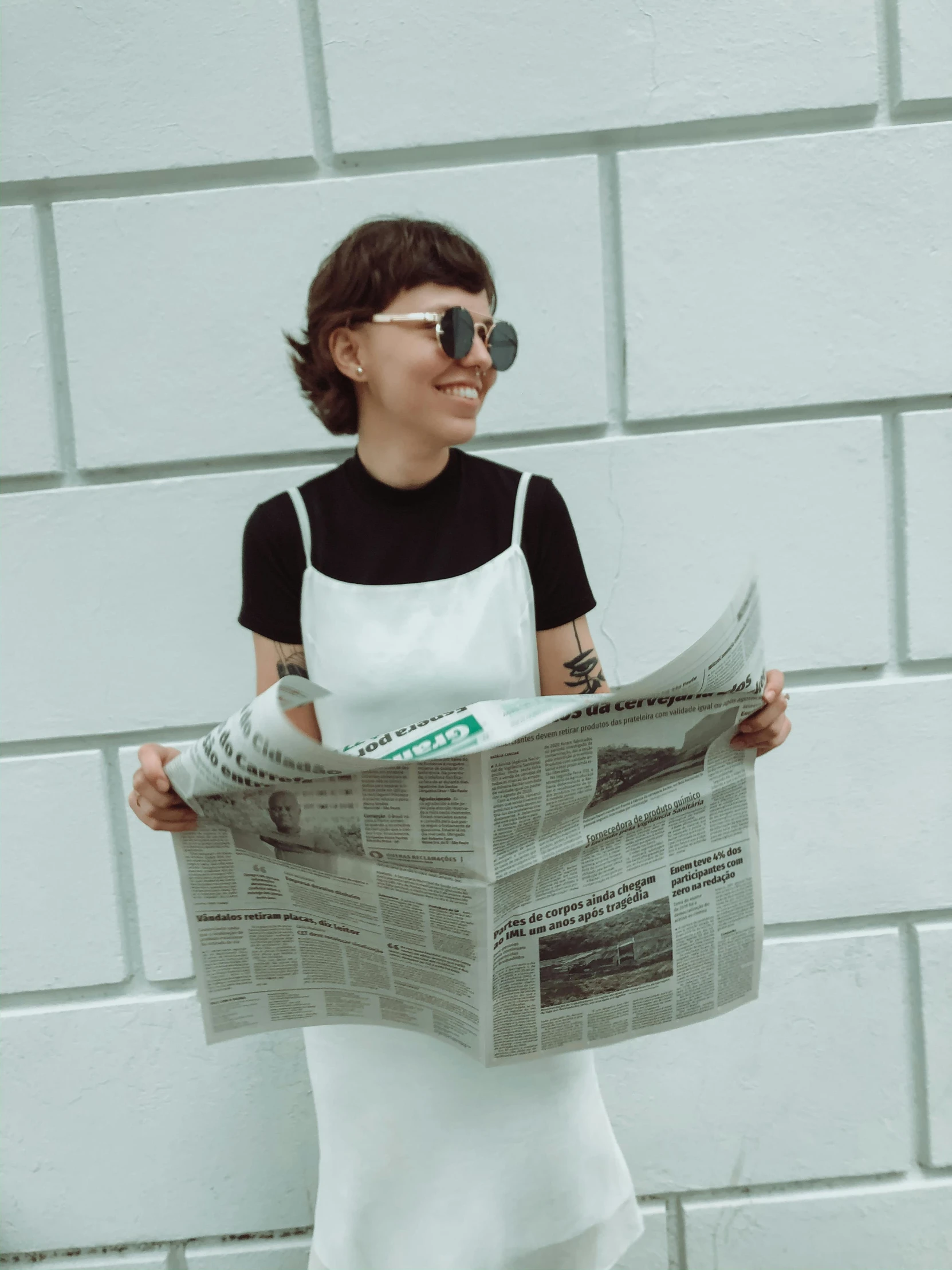 a girl wearing sunglasses reading the paper