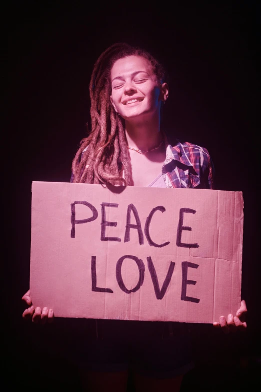 a person holding a sign that reads peace love