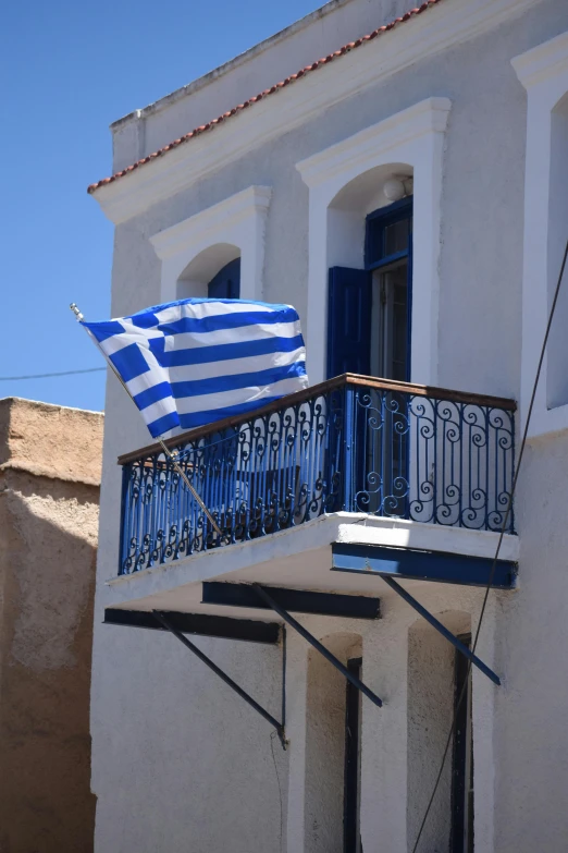 an outside balcony with a white building and blue door