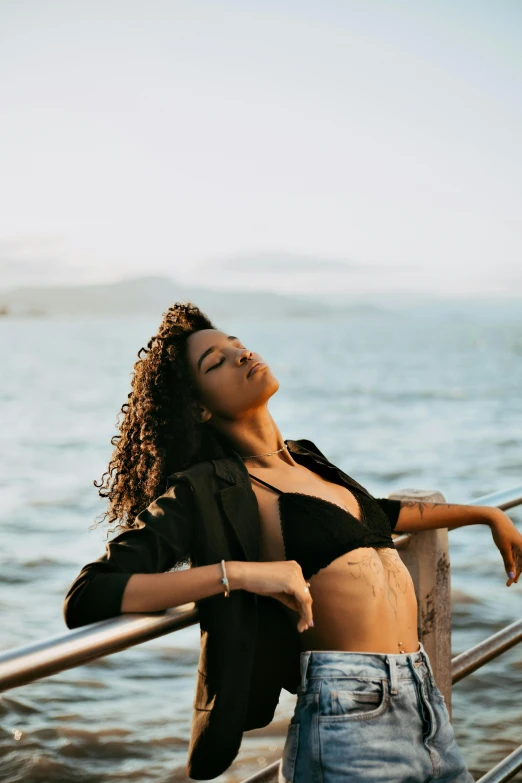 a woman standing on top of a metal rail next to the water