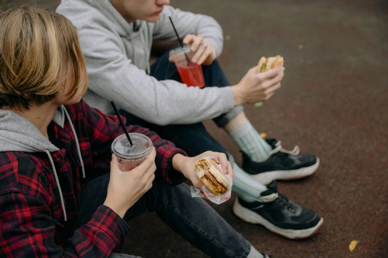 the young couple are sitting on the ground eating