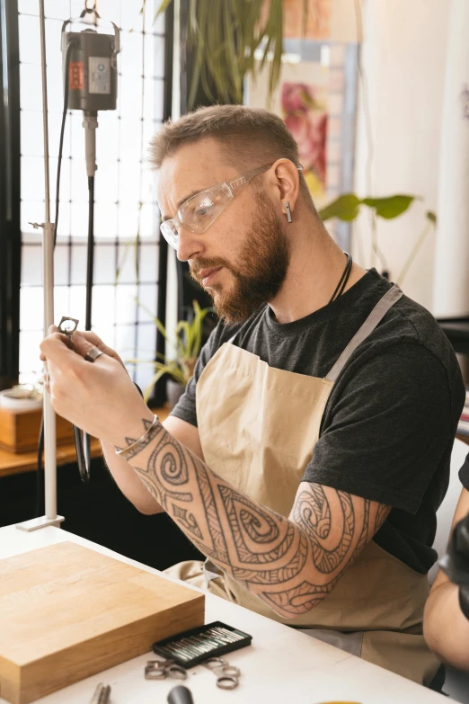 a man sitting at a table with tattoos working on soing