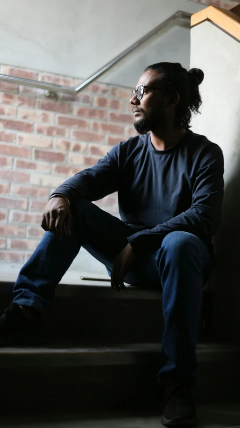 a man sitting down by a window with his foot on the steps