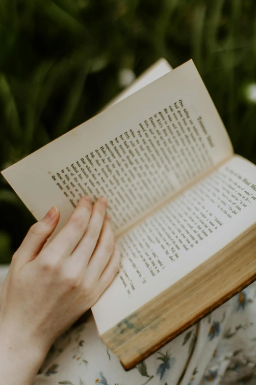 person holding open book looking down with her hands