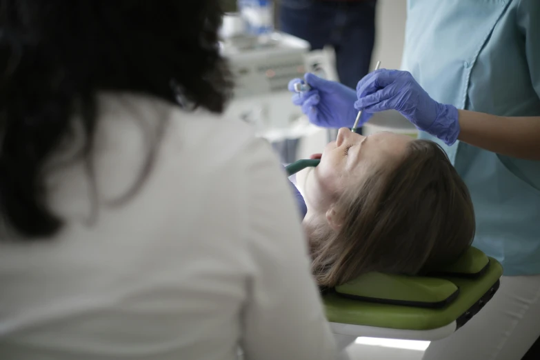 a woman laying on the ground while getting her teeth examined