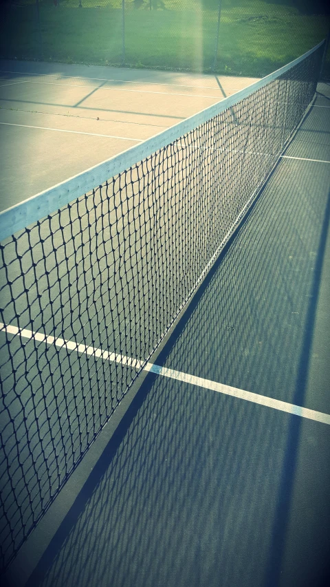 a tennis court net with the shadow of a man on the tennis court
