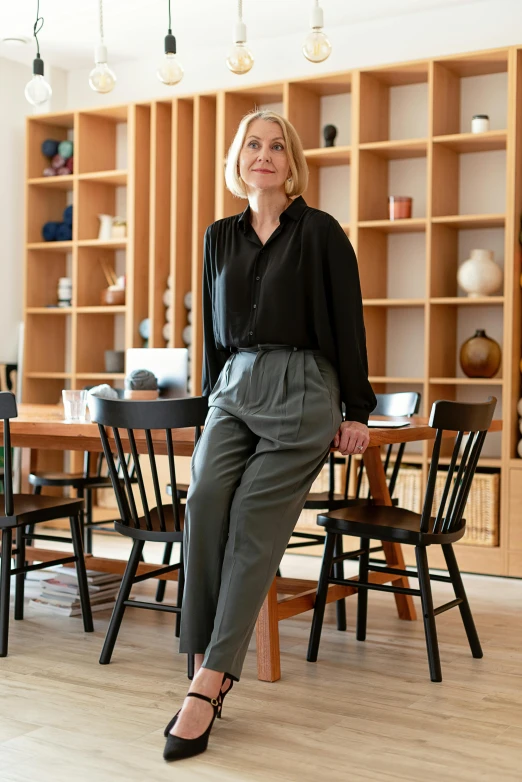 woman sitting on a chair wearing black blouse and green pants