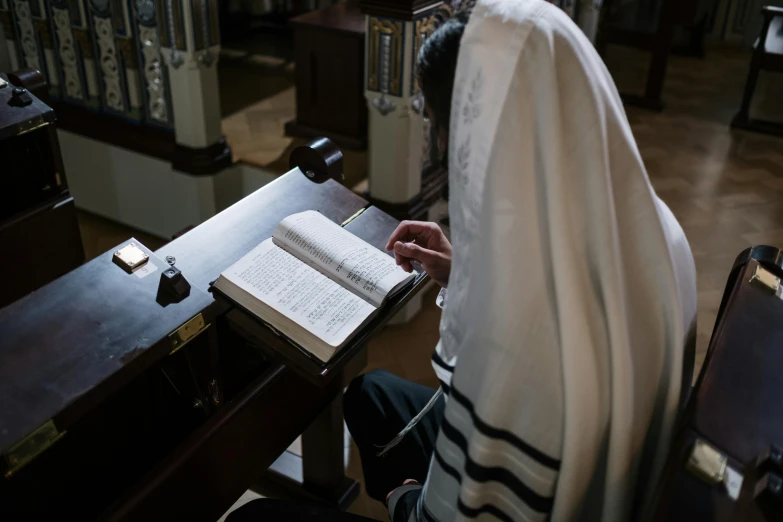 a person sitting at a table and reading an open book