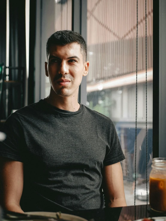 a man sits next to some food in front of his window