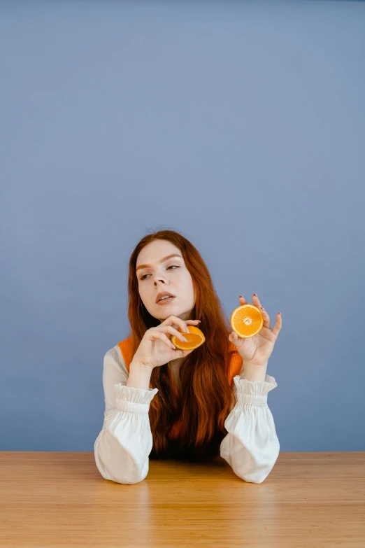 the woman is sitting at the table eating an orange