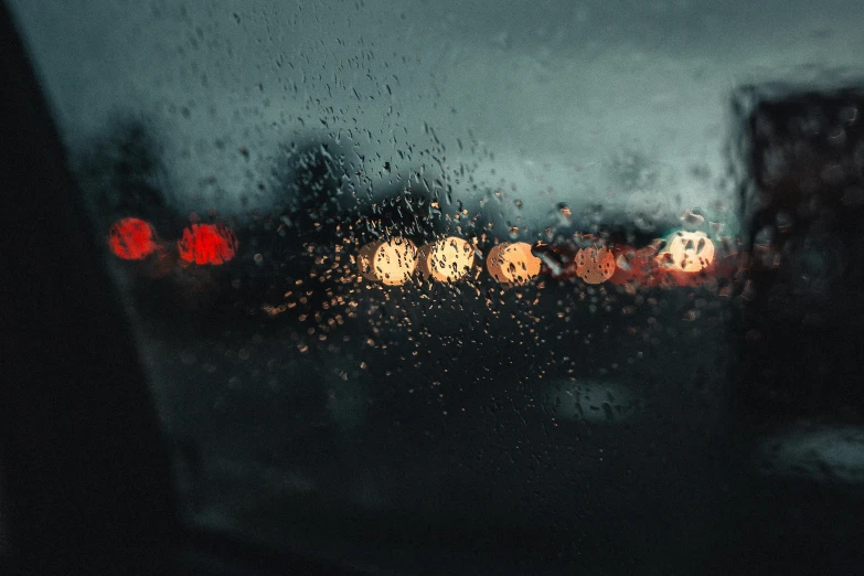 rain on a glass window next to traffic