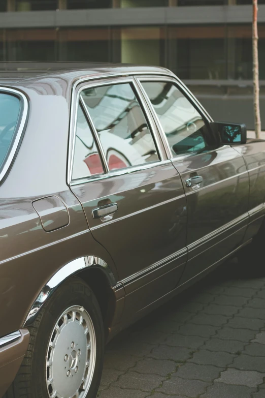 a brown mercedes parked next to a tall building