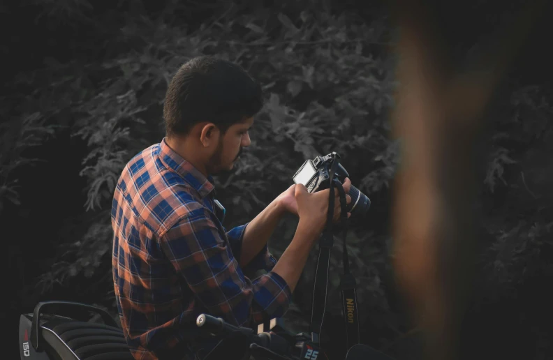 a person holding a camera next to trees
