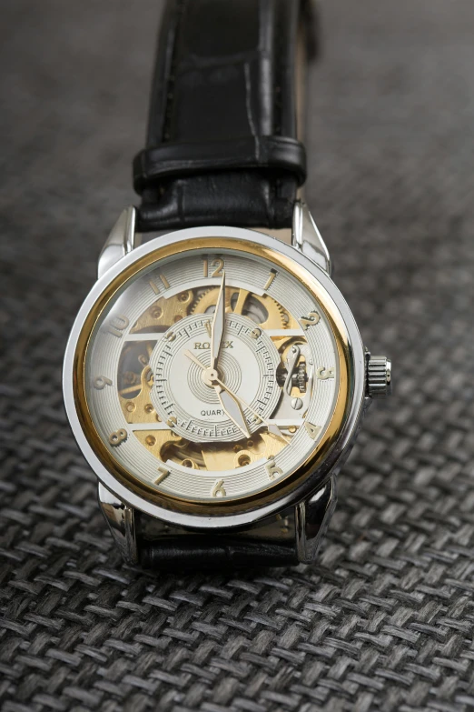 an analog mechanical watch sitting on the ground