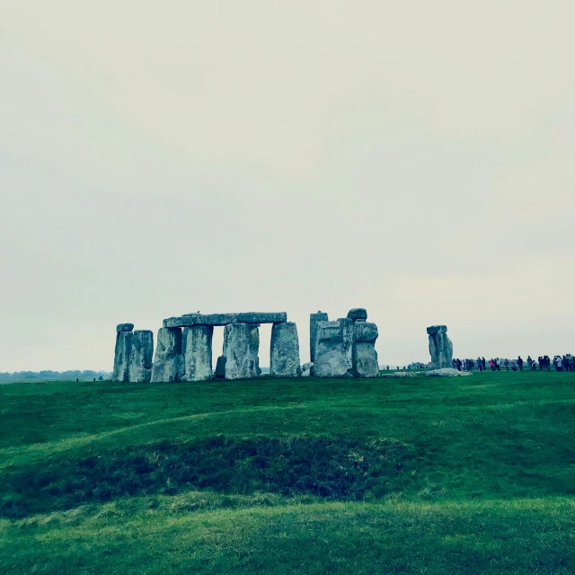 stonehenge standing on top of a hill next to people