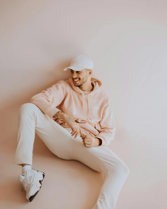 a man sitting on the ground wearing white pants