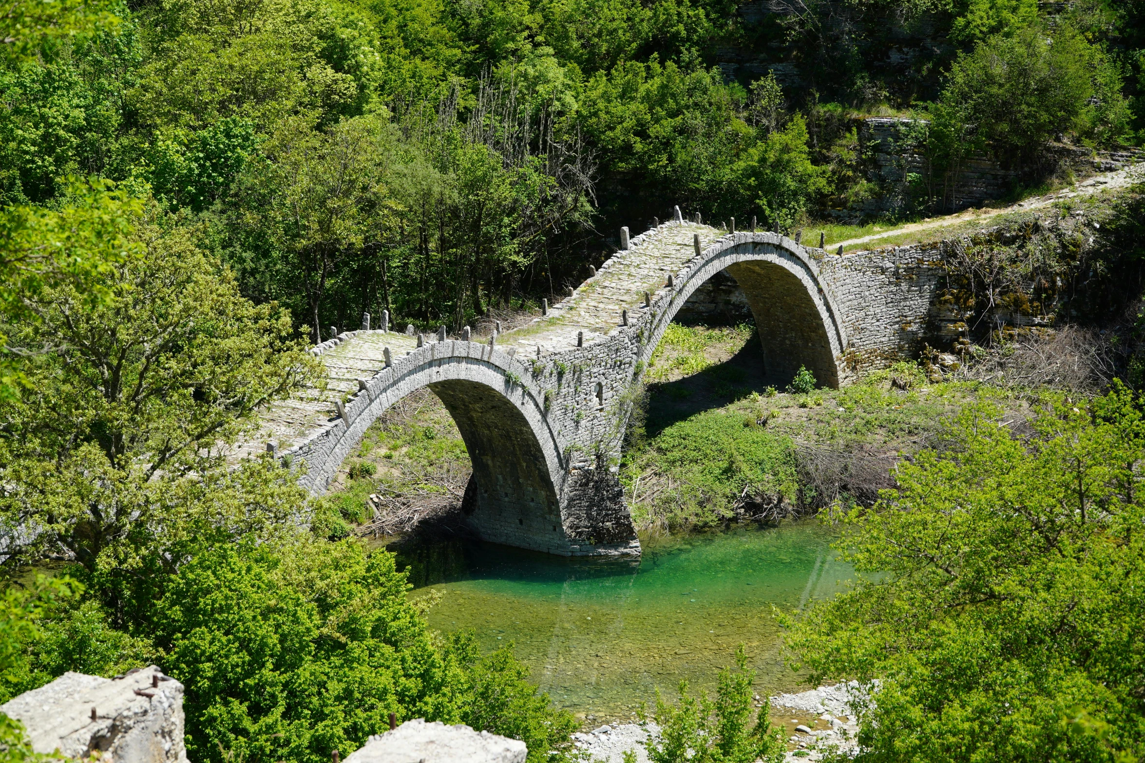 an old stone bridge crosses a river near some trees