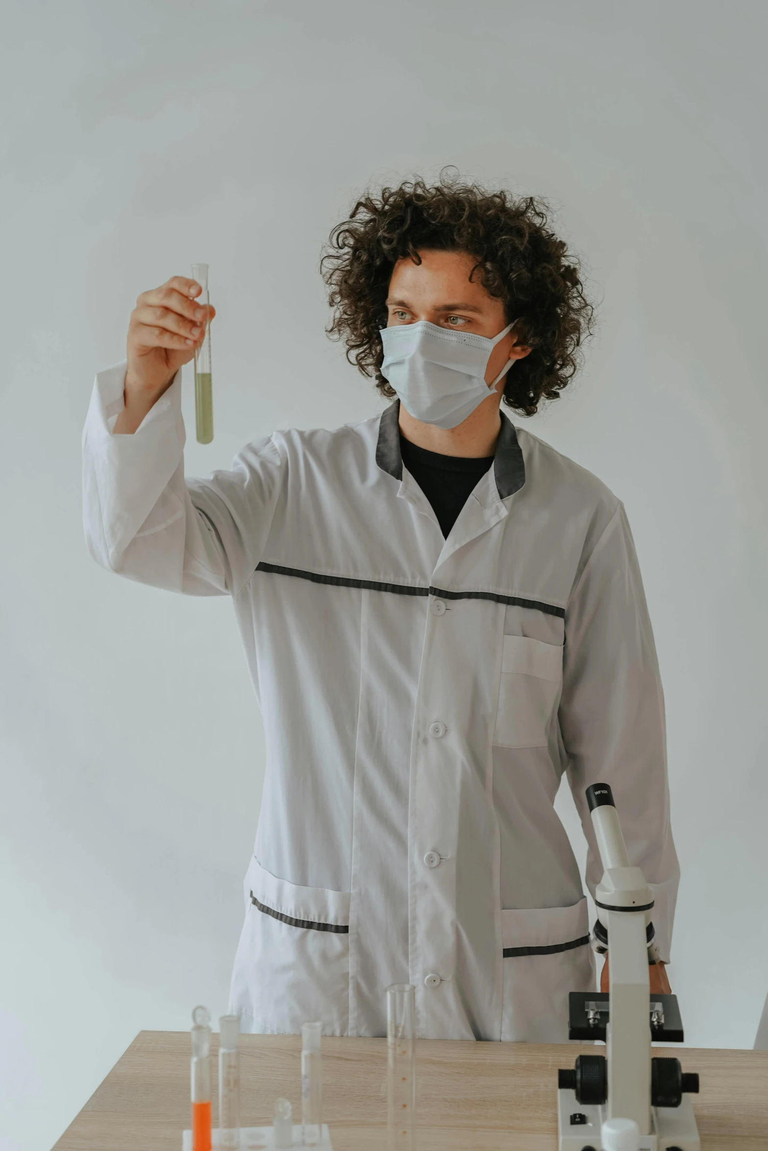 an african american man scientist holding up a glass tube containing liquid