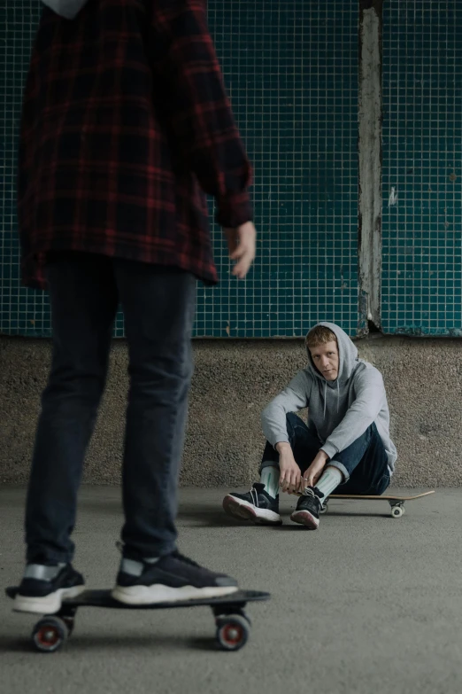 a young man sitting on a skateboard while holding his knee