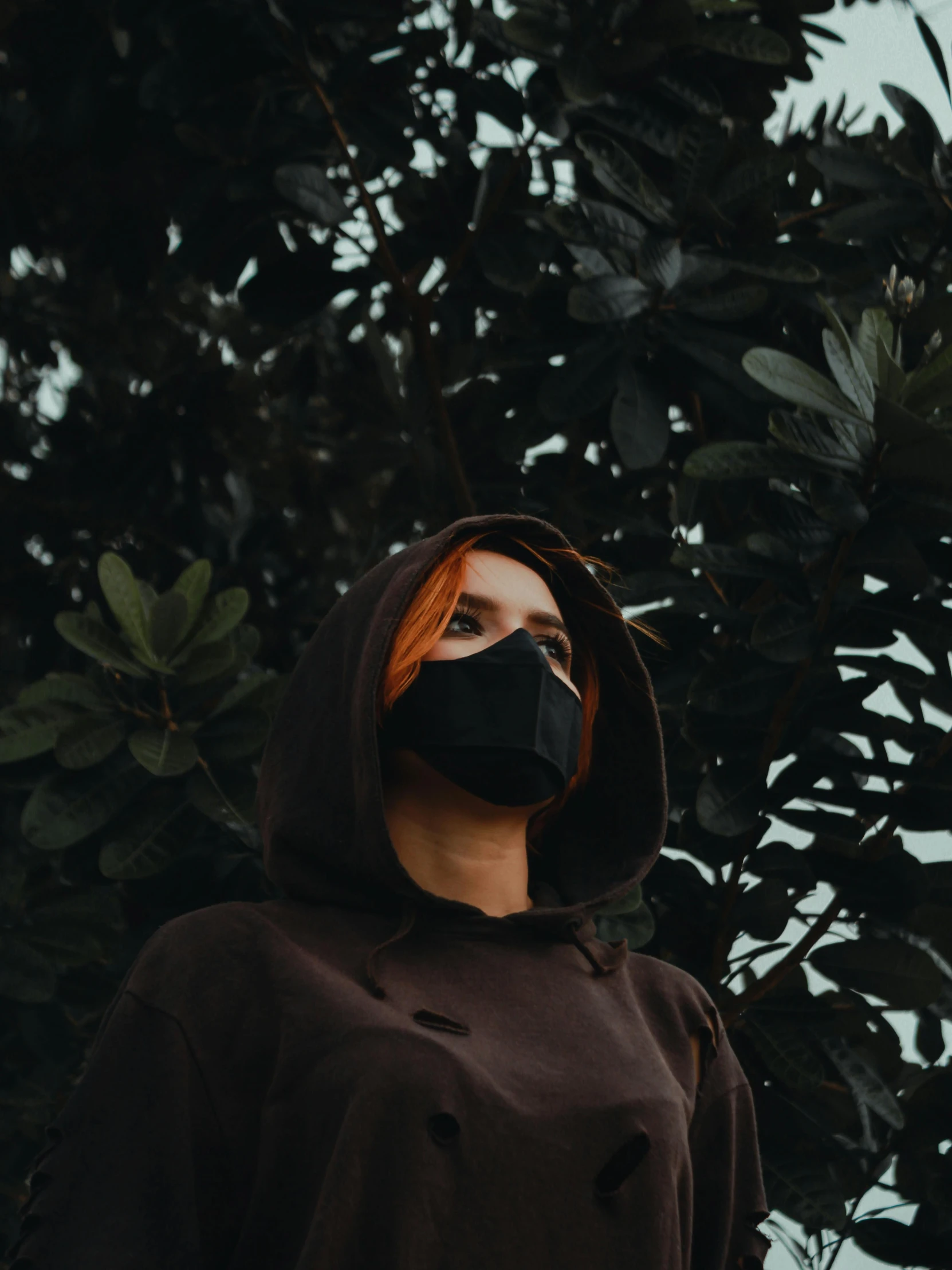 a woman wearing a black mask over her face and a hoodie on