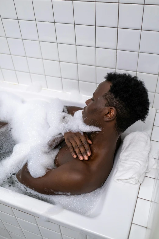 black man is washing himself in a bathtub full of foam