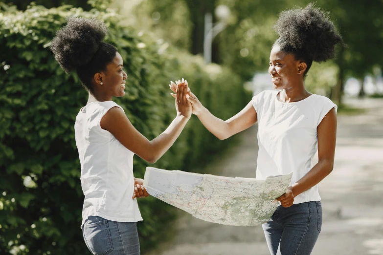 two woman, each hold a map and fist bump