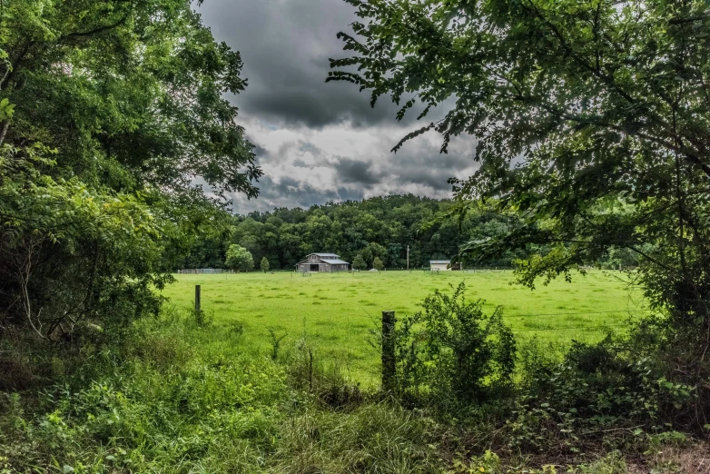 an open field with a farm on the horizon