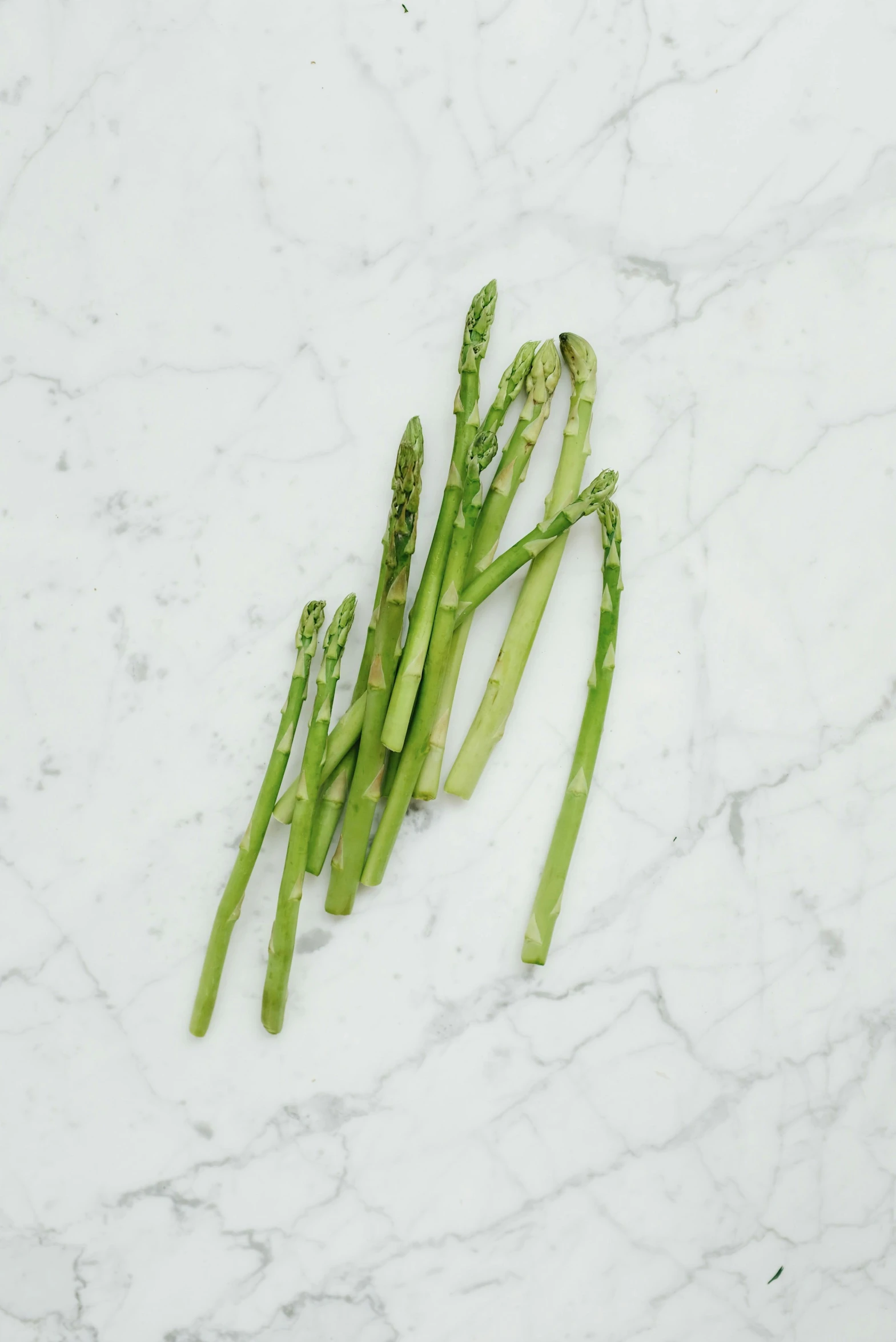 asparagus laid on a white marbled surface